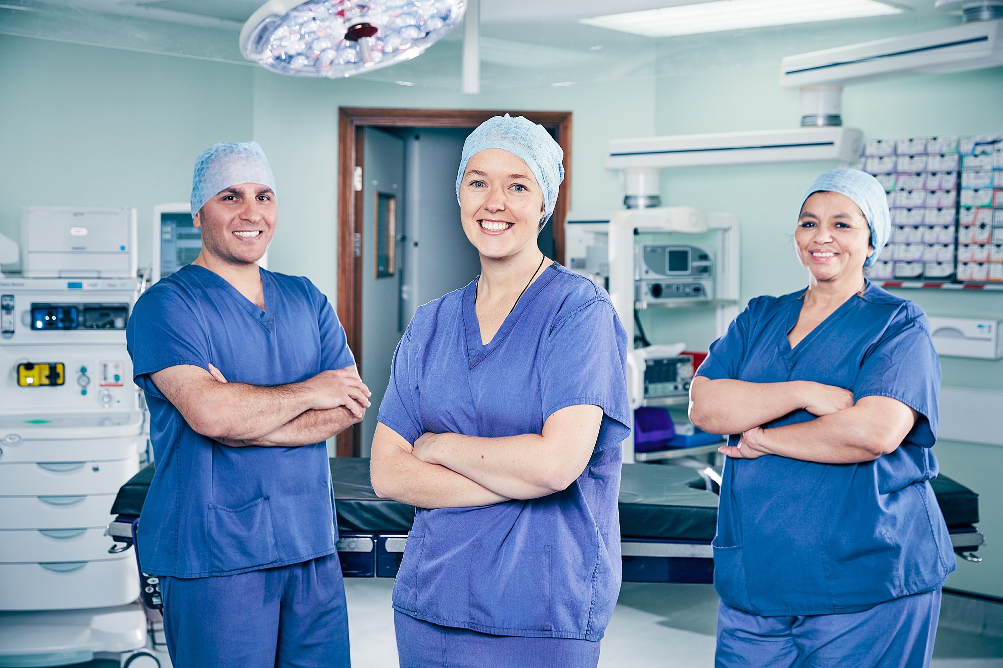 Three members of a surgical team in scrubs in an operating theatre