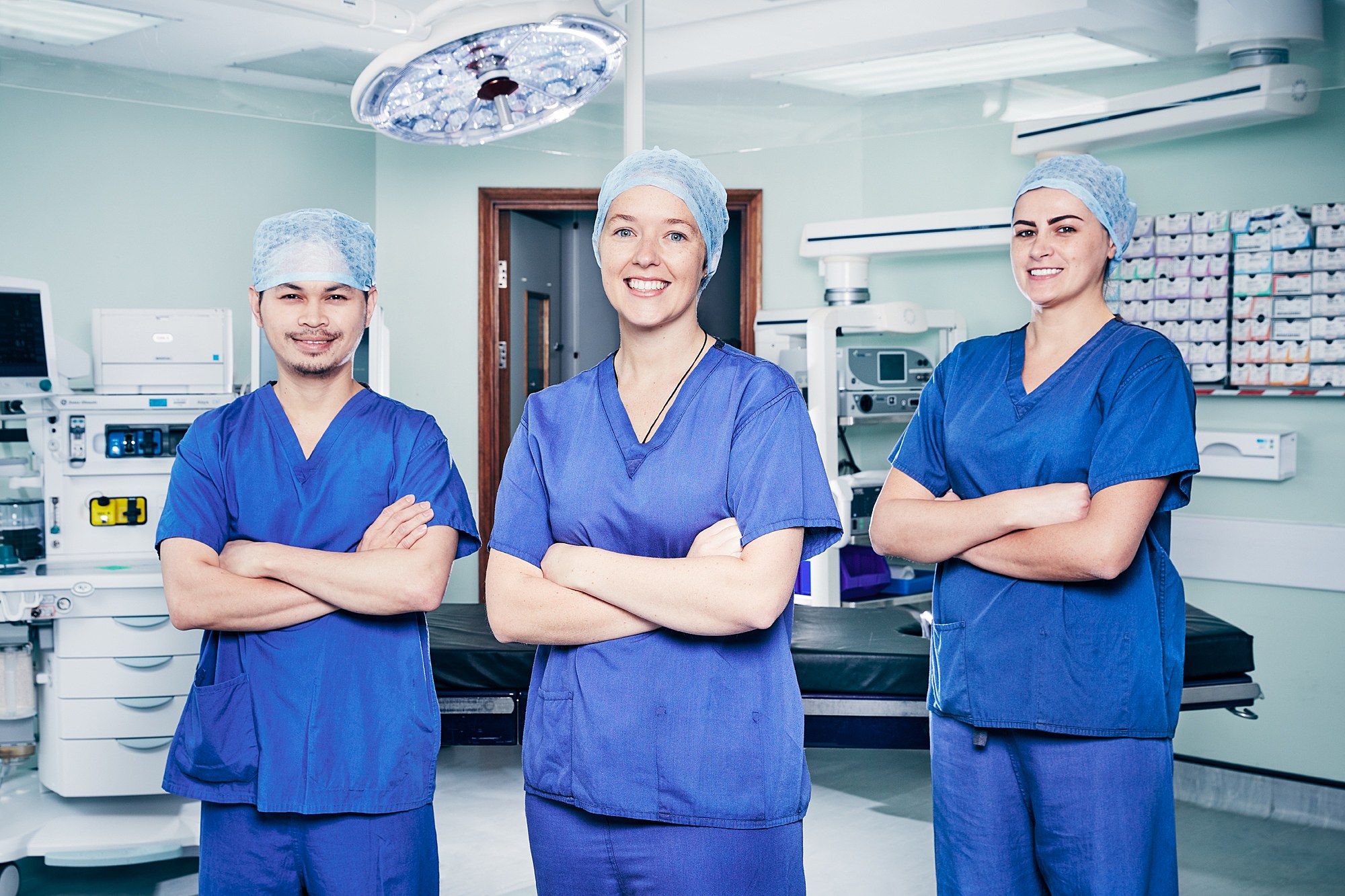 Three members of a surgical team in scrubs in an operating theatre